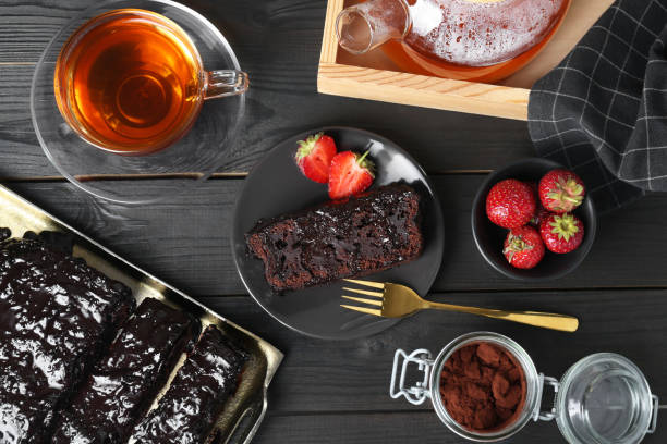istock Tasty chocolate sponge cake served on black wooden table, flat lay 1870421133
