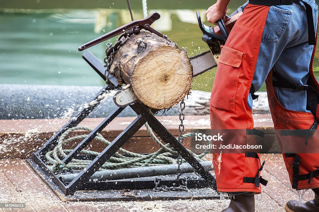 Man cutting a tree trunk with his chain saw Tree trunk being cut with a chain saw in Ketchikan, Alaska.  RM Alaska - US State Stock Photo