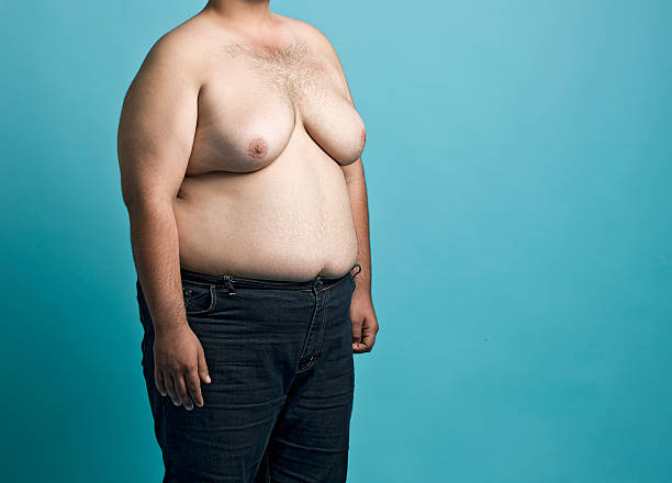 Obese young man Obese young man on blue background, midsection fat guy no shirt stock pictures, royalty-free photos & images