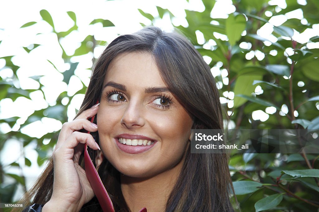 beautiful women using her mobile A natural beauty using her mobile phone in the garden. 20-24 Years Stock Photo