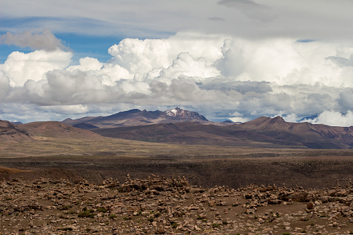 Beautiful view of the Altiplano, Peru, between Cabanaconde and Arequipa. High Altitude, mountain range, blue sky and white clouds, arid desert. Stones. Snow on the peaks.