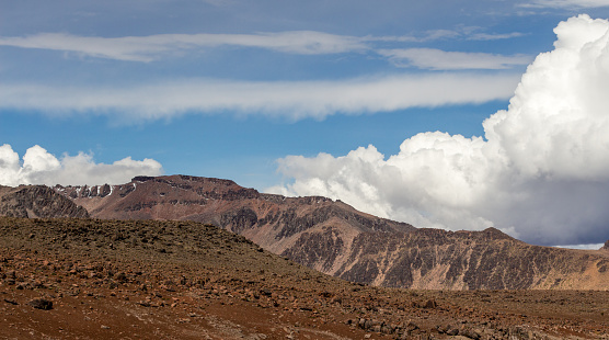 Spectacular rocky landscape in the Peruvian Altiplano in the Andes Mountains between Cabanaconde and Arequipa, Peru. Blue sky, huge white cloud.