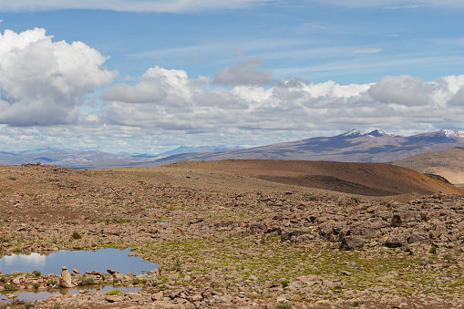 Spectacular landscape in the Peruvian Altiplano in the Andes Mountains between Cabanaconde and Arequipa, Peru. Brown hills, snowy peak. Blue sky, white clouds. Mountain range. Snow.