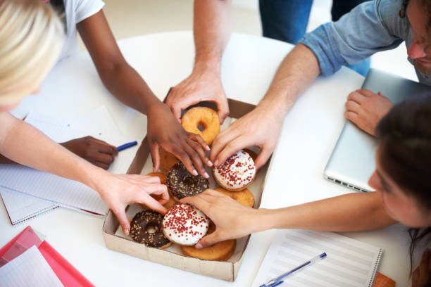 Creative minds deserve a treat Coworkers reaching for a tasty snack during a brainstorming session doughnut stock pictures, royalty-free photos & images