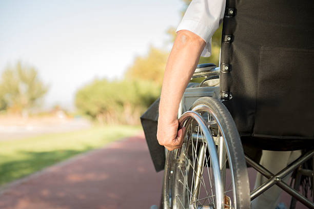 Man in wheelchair going down the sidewalk stock photo