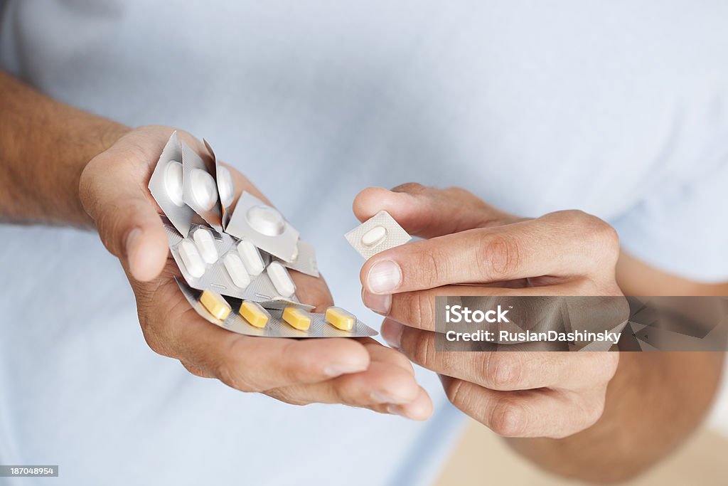 Hombre que agarra montón de pastillas. - Foto de stock de Hombres libre de derechos