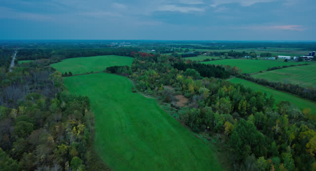 Forward Aerial Shot of Farmland Surrounded by Forest in Cheboygan County, Michigan on Overcast, Fall Evening