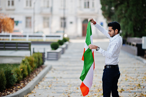 South asian indian male student with India flag posed outdoor.