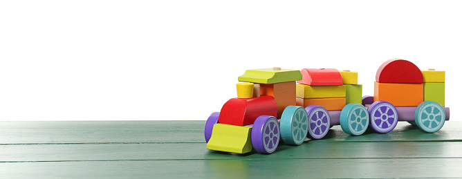 Colorful wooden train on green table against white background, space for text. Children's toy