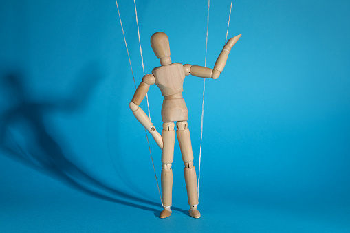 One wooden puppet with strings on light blue background