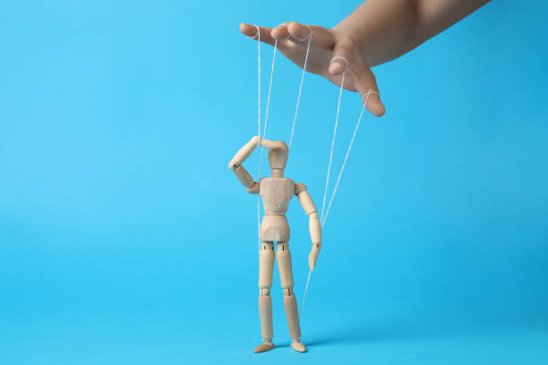 istock Woman pulling strings of puppet on light blue background, closeup 1870515059
