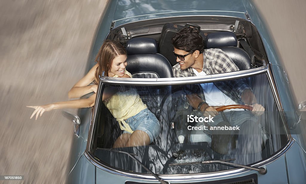 There's the place! High angle view of a young woman with her arms outstretched riding in a sports car with her boyfriend Couple - Relationship Stock Photo