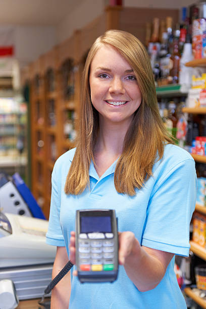 istock Female Sales Assistant Holding Credit Card Machine 187051933