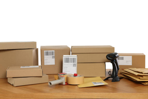istock Parcels, barcode scanner and adhesive tape on wooden table against white background. Online store 1870519765