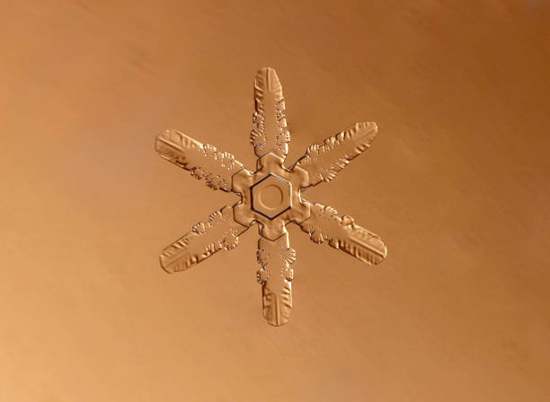 A small, symmetrical snowflake on gold background