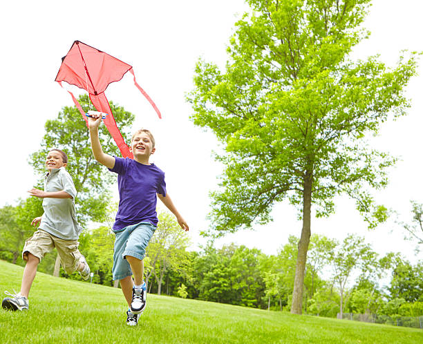 A happy young boy flying a kite outside in a park