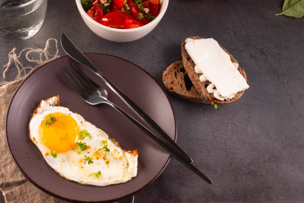 istock Fried eggs in broun plate with cheese sandwich and tomatoes salad  for breakfast 1870529618