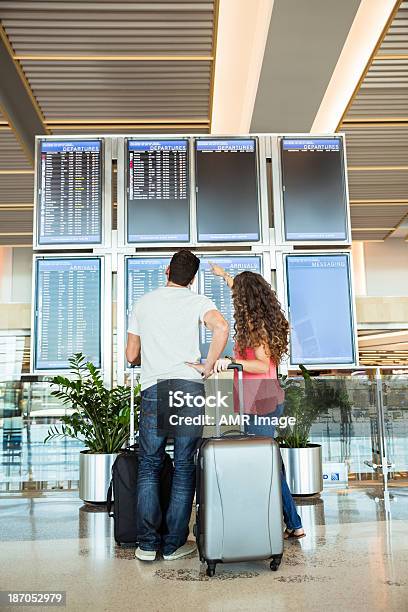 Casal Está A Verificar O Estado Do Seu Voo - Fotografias de stock e mais imagens de Adulto - Adulto, Aeroporto, Apontar - Sinal Manual