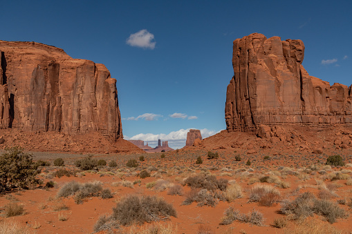 Tall spires and mesas of rich dark red rugged sandstone mountains near Monument Valley in Arizona and Utah of western USA in North America. This is part of the Navajo Native Indian Nation in USA.  Nearest cities are Phoenix and Grand Canyon Arizona, Salt Lake City, Utah, Denver and Durango, Colorado.