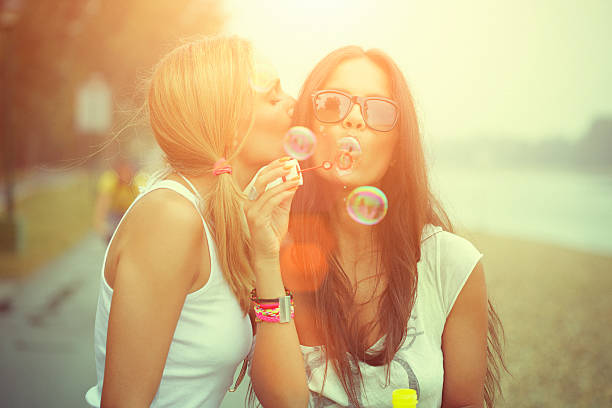 istock Two cheerful friends having fun and blowing bubbles 187054754