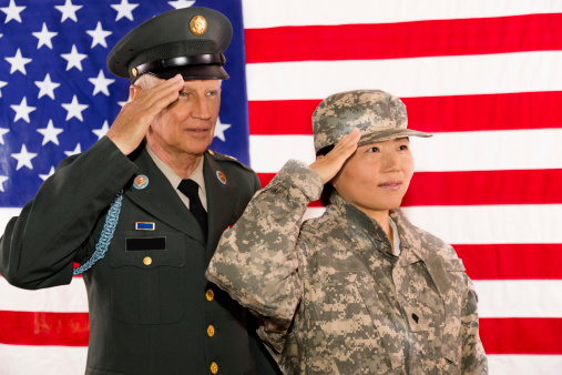 Senior army officer and soldier salute the American flag as a symbol of service to their country.