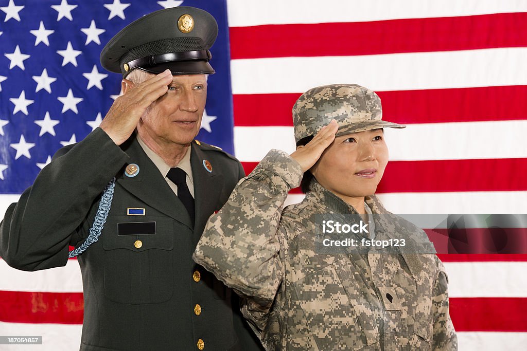 Military.  Army officer, soldier salute the American flag. Senior army officer and soldier salute the American flag as a symbol of service to their country. Veteran Stock Photo