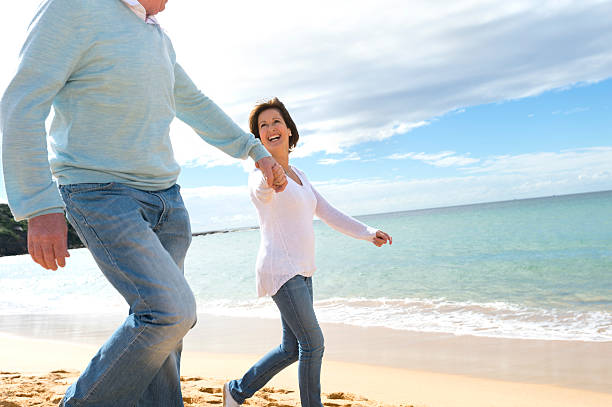 istock Happy mature couple walking along the beach 187054983