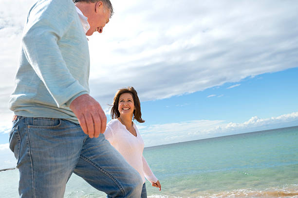 istock Happy mature couple walking along the beach 187054988