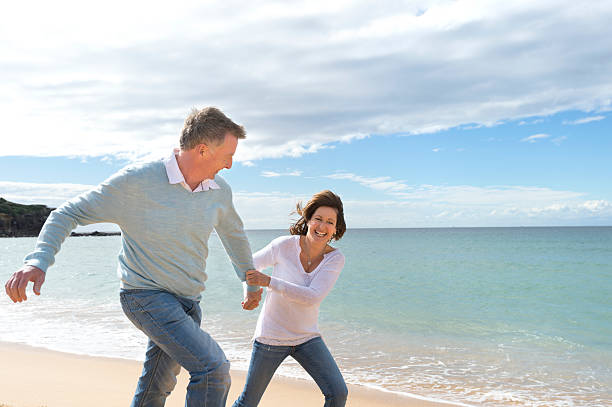Happy mature couple running along the beach