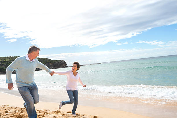 istock Happy mature couple running along the beach 187055019