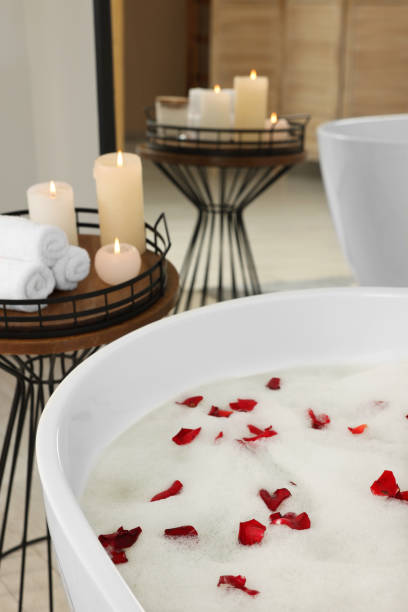 istock Bath tub with foam and rose petals in bathroom 1870550902