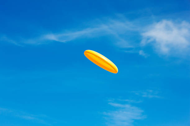 Flying, yellow frisbee in front of a clear sky. Single object. Summer. Clear sky. XXXL (Canon Eos 1Ds Mark III)