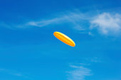flying yellow frisbee and clear sky