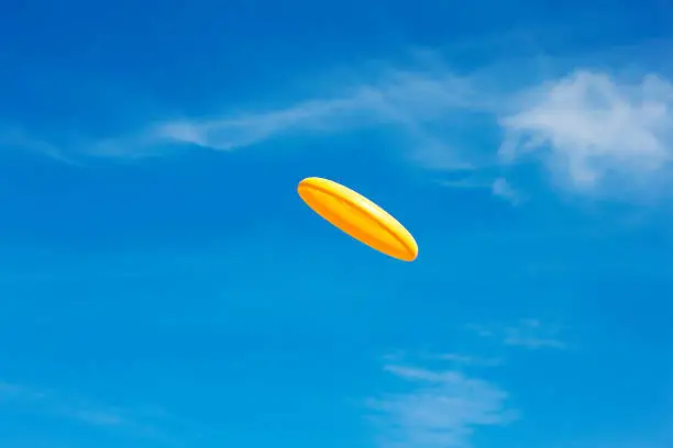 Flying, yellow frisbee in front of a clear sky. Single object. Summer. Clear sky. XXXL (Canon Eos 1Ds Mark III)