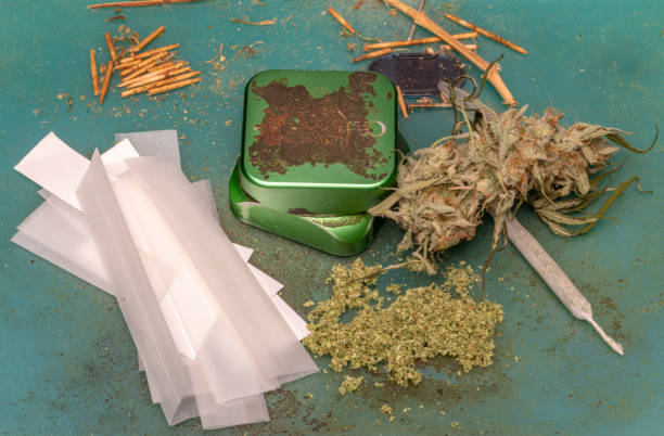 istock Rolling papers with green dry weed and joint with metallic grinder 1870557120