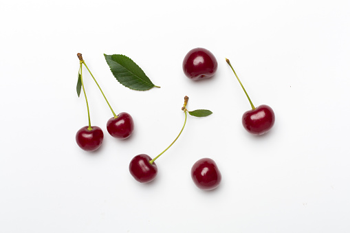 Cherries in a basket standing in a grass field.