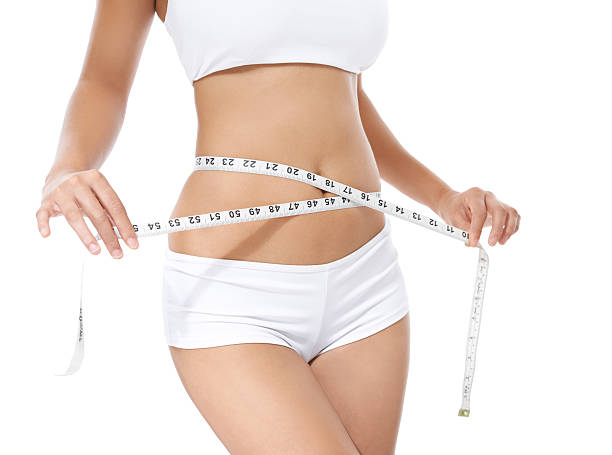 Dropping the kilos Cropped image of a young woman measuring her waist slim waist stock pictures, royalty-free photos & images