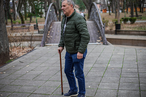 A senior man walks in an autumn public park