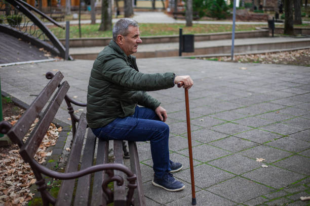 istock An elderly man is sitting on a bench in a public park 1870579388