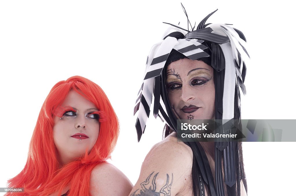 Man in cybergoth makeup and redhead looking at each other. Horizontal studio shot on white of two people back to back looking over shoulders at each other. 20-29 Years Stock Photo