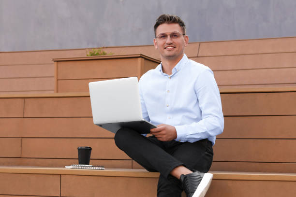 istock Handsome man using laptop on bench outdoors 1870608805