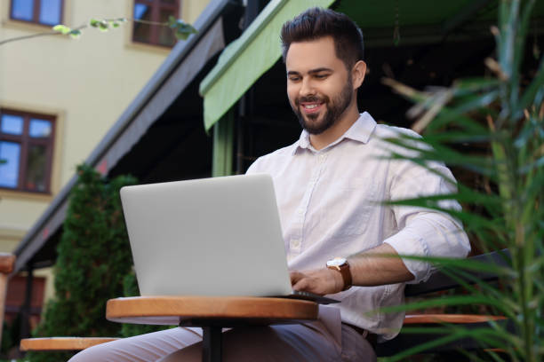 istock Handsome young man working on laptop at table in outdoor cafe 1870609862