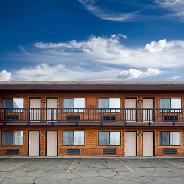 Front of two storey motel building with doors to the rooms.
