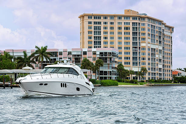 Large boat navigates waterway with apartment building in background A large boat navigates past a large apartment building in the background. rrRM delray beach fl stock pictures, royalty-free photos & images
