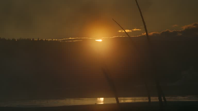 Wide Shot of a Hazy Landscape in Yellowstone National Park with Sun Setting in Background