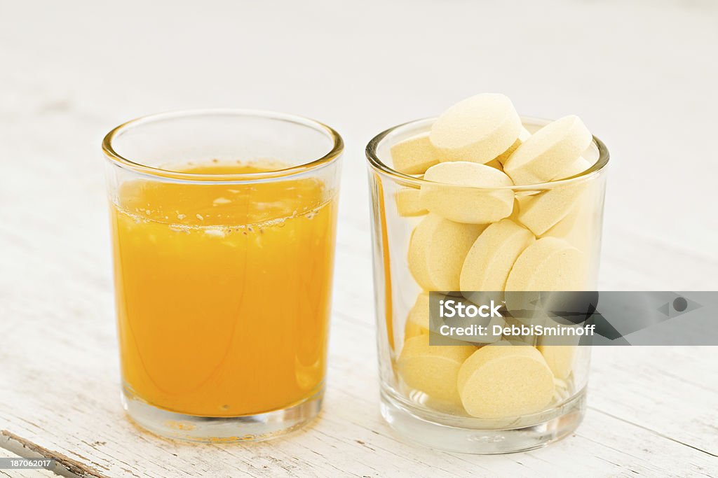 Orange Juice And Vitamin C Pills A close up shot of a glass of fresh squeezed orange juice next to a glass full of vitamin c pills. Pill Stock Photo