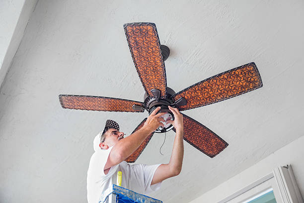 Real Electrician Hanging a Ceiling Fan  rr A real electrician stands on a ladder while finishing hanging a ceiling fan.  rr ceiling fan stock pictures, royalty-free photos & images