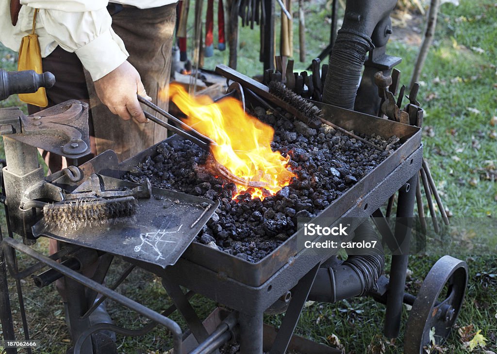 Ferreiro usa os pegadores para realizar horseshoe de incêndio. - Foto de stock de Brasa royalty-free