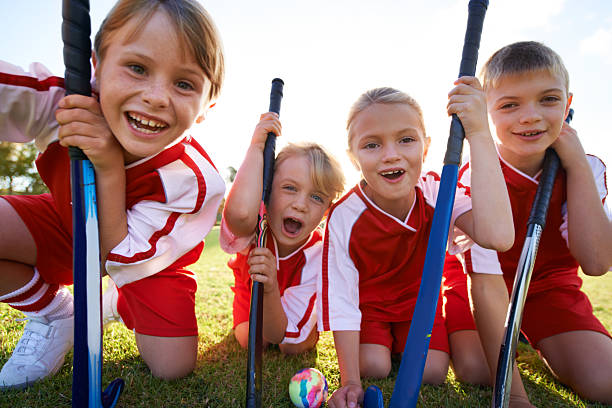 They've got strong team spirit! A team of young hockey players smiling at the camera field hockey stock pictures, royalty-free photos & images