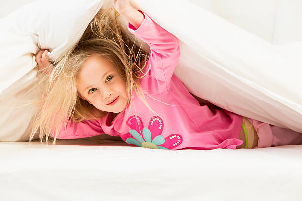 istock Little Girl Under Bed Covers 187063914